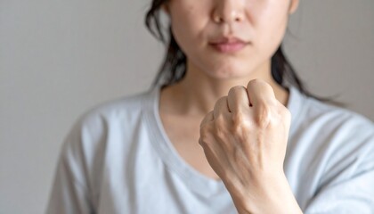 Fototapeta premium 胸の前に握りしめたこぶしを持ち緊張や決意を表現する女性のクローズアップ