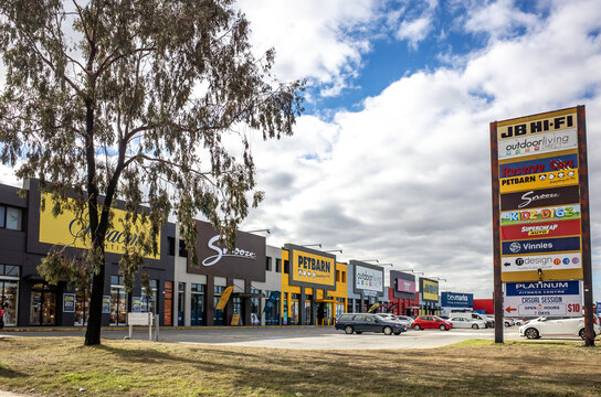 Retail strip with major chain stores and signage in Hoppers Crossing, Melbourne, Australia. Suburban commercial area featuring large-format retailers, parking spaces, signage. Car-oriented design.