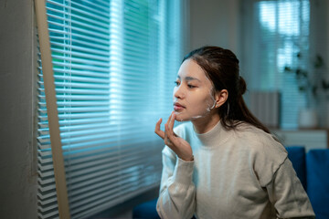 Fototapeta premium Young asian woman applying a face mask at home