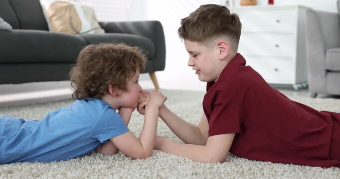 Two brothers arm wrestling on floor indoors