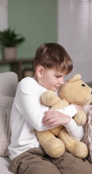 Little boy with his teddy bear on sofa at home