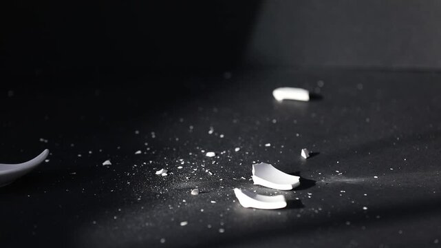 Porcelain cup falling onto saucer and breaking on black background, closeup
