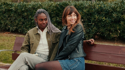 Lesbian Couple Relaxing On Park Bench Together
