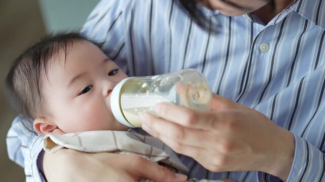 赤ちゃんにミルクを与えるお父さん