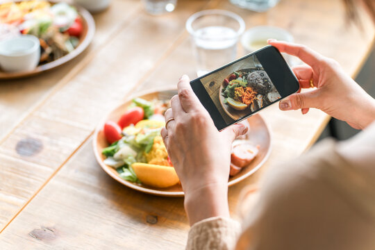 A hand taking a picture of food with a smartphone
