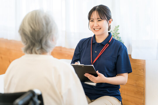 A female caregiver interviews a senior woman in a wheelchair.