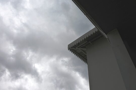 The hanging fascia on the roof of a tall, traditional themed building often found in joglo houses or colonial style buildings with a cloudy morning sky as a backdrop.