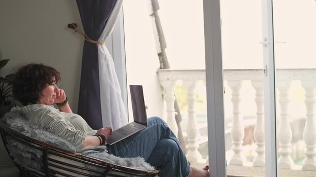 Individual Making Phone Call Outside On Balcony. Woman Talks On Her Phone While Relaxing Outdoors On Balcony. Woman In Casual Attire Discusses Something On Her Phone During Short Outdoor Break