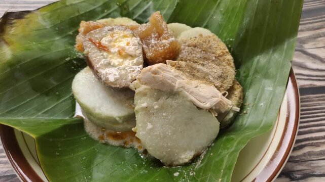 Lontong opor is a traditional Indonesian dish consisting of slices of lontong topped with a savory chicken opor sauce. It is served with shredded chicken, krecek, and pindang egg.