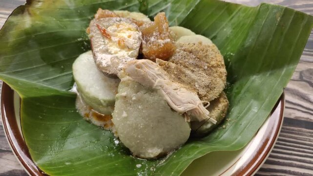 Lontong opor is a traditional Indonesian dish consisting of slices of lontong topped with a savory chicken opor sauce. It is served with shredded chicken, krecek, and pindang egg.
