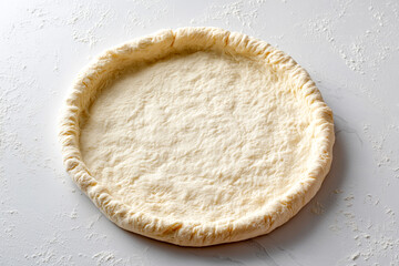 Fresh raw pizza dough base with a thick crust on a white floured marble surface. High quality culinary shot representing Italian cooking, homemade bakery, and food preparation