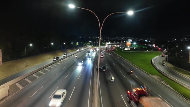 Real-time wide shot of vehicles driving through the main expressway of Caracas with city lights and mountains