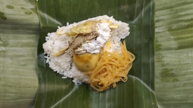 A delicious Nasi Liwet served on fresh banana leaves. Nasi Liwet Solo is a traditional dish from Surakarta or Solo, Central Java, Indonesia, consisting of fragrant rice cooked with coconut milk.