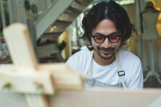 Cheerful Japanese man with beard smiling while painting watercolor at home