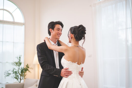 Happy Asian wedding couple dancing together during romantic ceremony