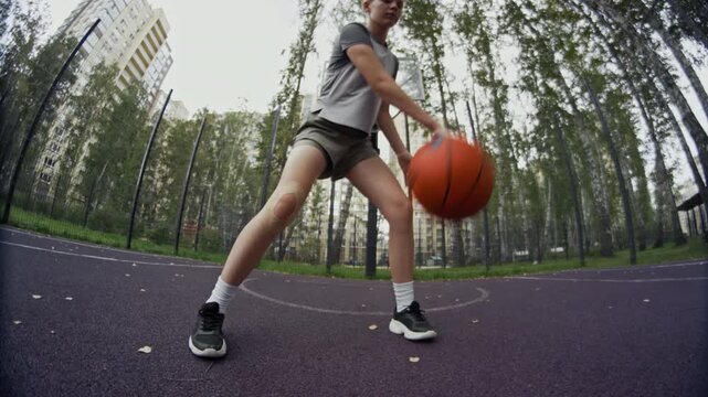 Cinematic cropped shot of unrecognizable teenage girl dribbling ball and doing trick in urban outdoor court, youth culture concept, copy space