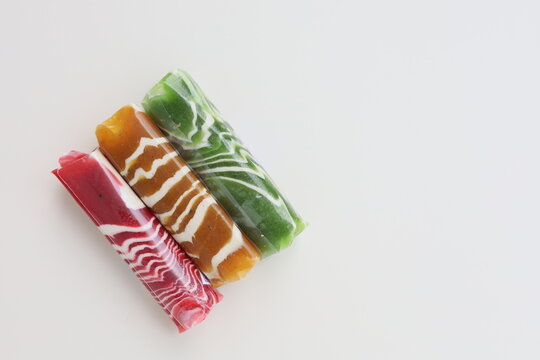 Three pieces of Dodol Garut, traditional Indonesian sweet taffy, with colorful striped patterns in red, green, and brown, isolated on a white background.