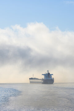 Bulk carrier cargo ship in Puget Sound on a foggy morning with air full of exhaust and pollution, global shipping of trade goods worldwide, import and export in the international economy
