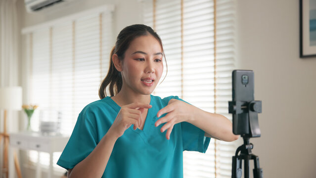 Young adult woman asia people anti aging expert modern nurse live talk video call selfie camera mobile phone app mental health care Online digital virtual asian vlogger filming hand wrist pain physio.