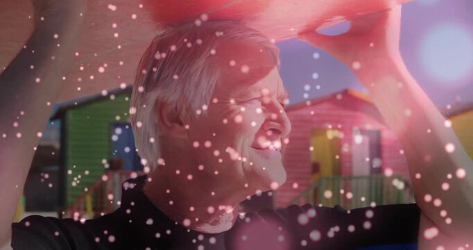 Holding pink shade, senior in dark top squinting with sunlight hitting face, bokeh at beach huts