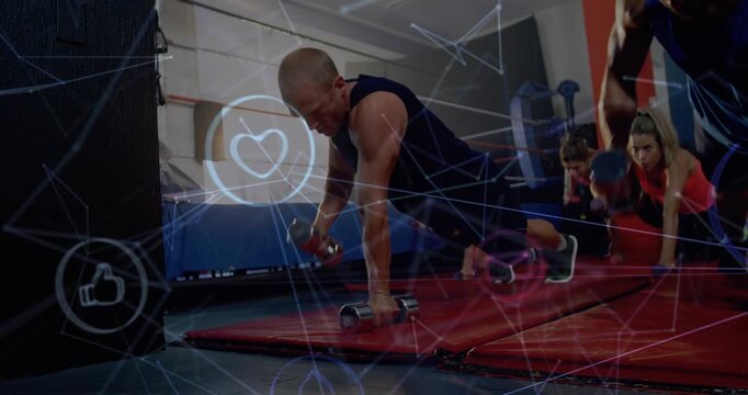 Lead male initiating plank rows with weights on mats, group mirroring for fitness, icons overlaying