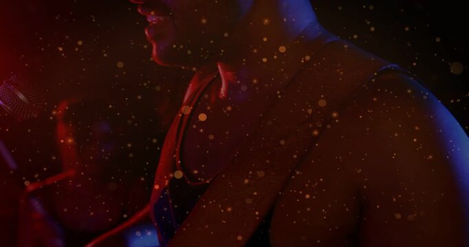 Female adjusting strap, male joining mic, singing music, red blue lighting, gold-speckle drifting