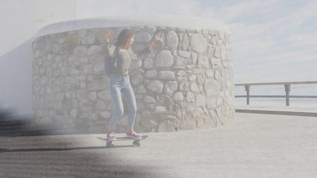 Woman skateboarder pushing back coasting shore path to rail overlay partly obscuring her for travel