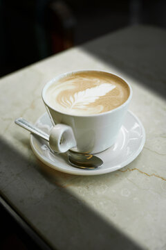 Eine Tasse Latte Macchiato auf einem Tisch in einem Cafe mit Sonnenlicht am Fenster