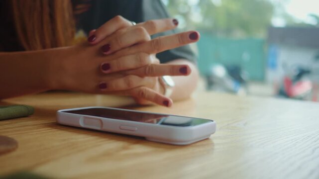 Woman puts smartphone on table and locks her hands choosing digital detox. Conscious pause from social media reduces stress improves focus mindfulness and mental health in modern cafe lifestyle scene
