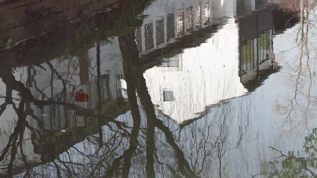 The reflection of traditional Chinese white wall building and willow trees in river in sunny spring day, 4k slow motion footage b roll shot.