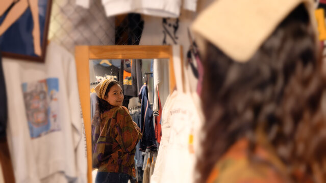 Young tourist Gen Z asia female choose look at zero waste eco go green buy second hand sale store flea market thrift old used vintage street hat style. Happy woman city asian people small retail shop.