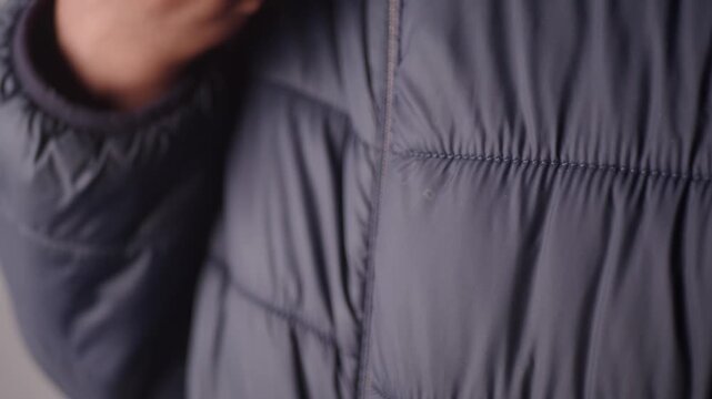 A man zipping up his jacket in close up footage dynamic motion slow motion shot.
