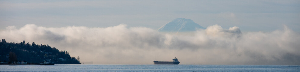 Bulk carrier cargo ship in Puget Sound on a foggy morning with air full of exhaust and pollution, Mt. Rainier in background, global shipping of trade goods worldwide, import and export  © knelson20