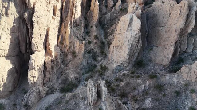 Cinematic close-up of a rugged rocky mountain cliff side with dramatic textures and vertical drops.