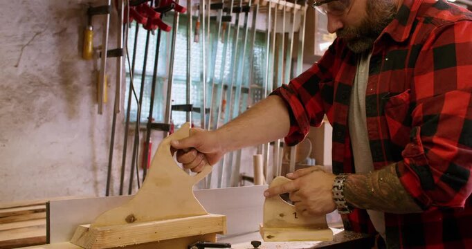 Carpentry workflow. Jointer machine. Male worker with safety glasses smoothing fresh cut plank on professional electric equipment.