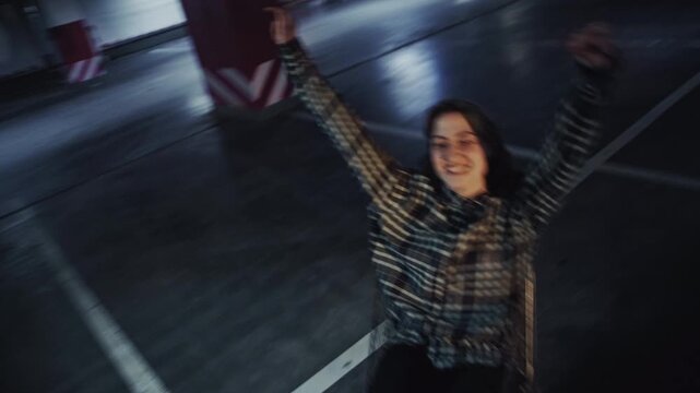 Two lovers act like kids, using a shopping cart as an improvised ride in a parking lot. The guy pushes his girlfriend, both smiling and enjoying a spontaneous, fun moment together.