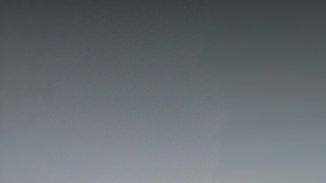 A subtly textured grey gradient, with small light dot clusters