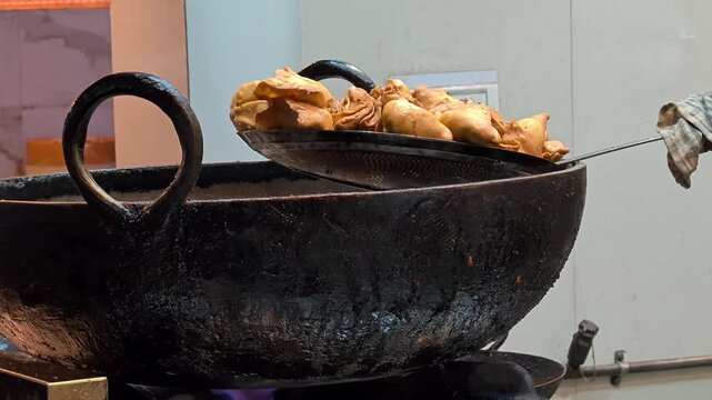 Street food vendor deep frying traditional Indian samosas