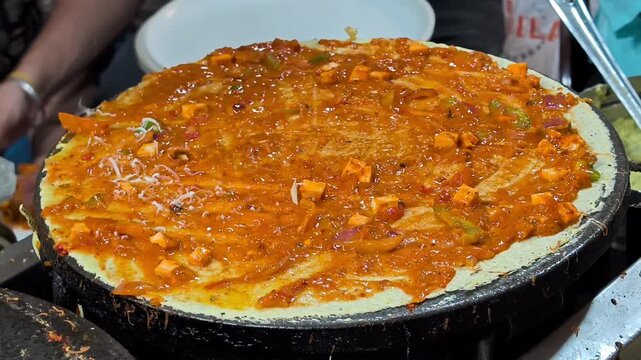 Indian street food vendor preparing dosa on hot tawa
