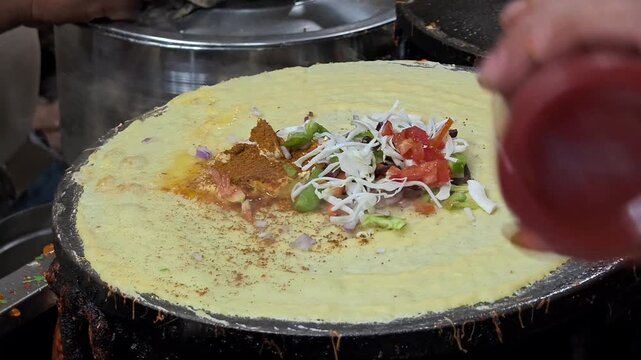 Indian street food vendor preparing dosa on hot tawa