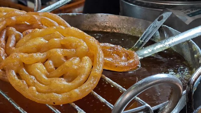 Indian sweet jaleba being deep fried and soaked in sugar syrup at street market
