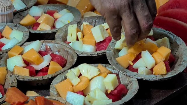 Vendor hand arranging fresh cut fruit