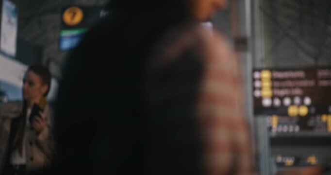African American Man Stands In Brightly Lit Airport Terminal, Using Smartphone to Scan Digital Boarding Pass. Male Carefully Reviews Flight Details, Gate Numbers, and Departure Time on His Screen.