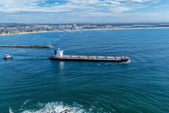 Aerial drone view of a large cargo ship departing Newcastle Harbour in New South Wales, Australia.