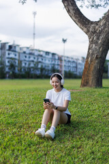 Fototapeta premium Young woman enjoying music on smartphone in park