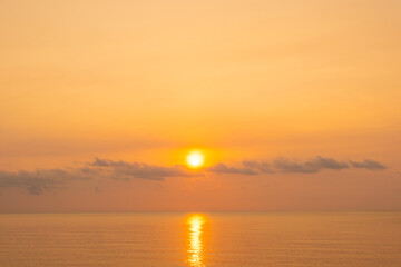 Fototapeta premium nature sky breathtaking golden sunset over a calm ocean, with the entire sky and water bathed in brilliant shades of yellow and orange. Streaky clouds enhance the dramatic display 