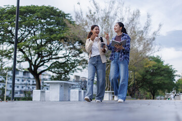Obraz premium Asian college students walking and chatting in park
