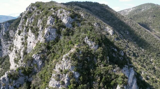 Aerial drone footage over Frasassi Gorge, Italy: rocky cliffs, green vegetation and dramatic natural landscape. Ideal for travel, nature and geological projects.