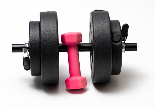Small dumbbell and big dumbbell on white background. Heavy black big dumbbell and light small dumbbell. Sport dumbbells equipment.