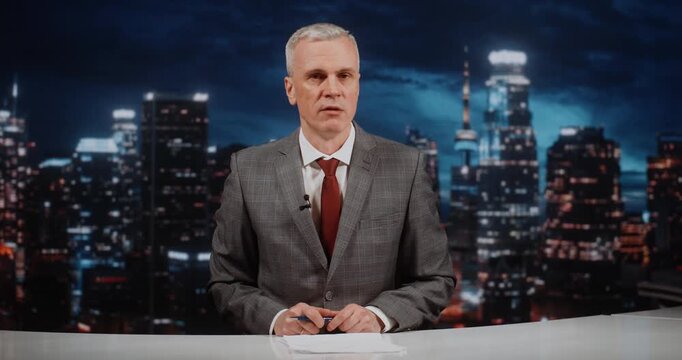 Male Anchor in Grey Suit Hosts Weekly Analytical News Program in Modern Studio. Man Analyzes Key Political and Economic Topics, Providing Expert Commentary and Summarizing Main News For Wide Audience.